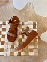 Sandalias de plataforma corrida color marrón con tira delantera simple, tira en el empeine y tira al tobillo con hebilla metálica.