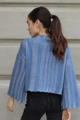 Sweater tejido de punto a rayas horizontales negras y plateadas, con cuello alto, mangas tres cuartos y calce oversize.