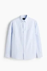 Camisa de algodón H&M Oxford con estampado de rayas verticales celestes y blancas, cuello americano, bolsillo en el pecho y manga larga.