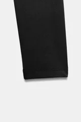 Body de manga larga con escote cuadrado, confeccionado en tejido elástico con cierre inferior mediante botones a presión.