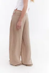 Pantalón sastrero de lino italiano color beige, de corte recto y holgado, con aberturas laterales en la cintura y pinzas.