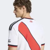 Camiseta de fútbol Adidas del River Plate, modelo local, color blanco con la característica banda diagonal roja, detalles en negro y cuello redondo.