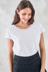 Remera negra de algodón peinado, ajustada al cuerpo, con cuello redondo y detalles de vainillas caladas en el escote y los hombros. Las mangas son cortas y están dobladas hacia afuera.