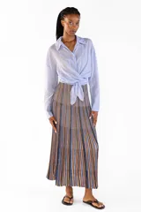 Camisa de manga larga color celeste, confeccionada en algodón, con cuello clásico, cierre frontal de botones y diseño cruzado con lazo para anudar en la cintura.