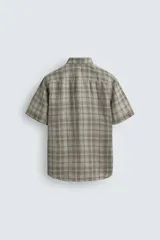 Camisa de lino color beige de corte relajado, con cuello solapa, manga corta y cierre frontal con botones.