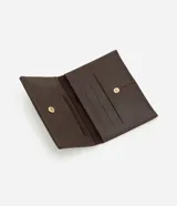 Billetera tipo sobre de diseño compacto, confeccionada en poliuretano con textura que imita el cuero. Presenta un cierre con botón a presión y costuras decorativas verticales en el frente.