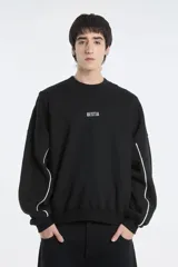 Buzo negro de corte holgado con cuello redondo y detalle de línea blanca curva en las mangas.