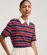 Chomba de algodón con diseño de rayas horizontales en tonos azul marino y rojo, cuello polo en color blanco con botones frontales y mangas cortas.