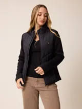 Campera híbrida con frente acolchado y mangas y laterales de tejido scuba. Presenta cierre frontal, cuello alto y un pequeño logo bordado en el pecho.