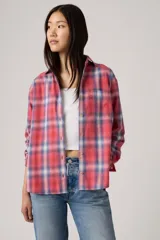 Camisa de franela a cuadros en tonos rojo, azul y blanco, con cuello clásico, cierre de botones frontales y un bolsillo en el pecho.