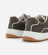 Championes urbanos de estilo street, confeccionados en material sintético color gris oscuro con detalles en blanco. Presentan cierre mediante cordones, recortes laterales decorativos y una suela de plataforma blanca con base color caramelo.