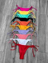 Colaless de bikini con cobertura mínima, estilo brasileño, con tiras ajustables laterales para atar. Disponible en varios colores sólidos.