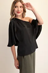 Top negro con diseño asimétrico de un solo hombro y manga tipo capa fluida. Confeccionado en tela ligera y suave, presenta un corte elegante que se ajusta al cuerpo.