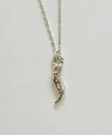 Collar de plata con cadena fina de eslabones y dije en forma de cuerno o amuleto de la suerte.