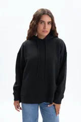 Canguro deportivo de color negro, con capucha ajustable mediante cordones, mangas largas y corte holgado.