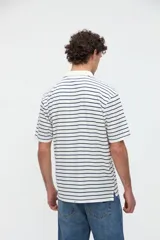 Remera polo de manga corta con diseño a rayas horizontales marrones sobre base blanca, cuello camisero en color blanco con media cartera de botones y aberturas laterales en el dobladillo.