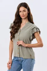 Camisa de lino y viscosa color beige, con cuello mao, escote en V y botones frontales de madera. Presenta mangas cortas con volados delicados.