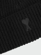 Gorro tipo beanie de lana en color negro, con diseño de punto acanalado y vuelta en el borde.
