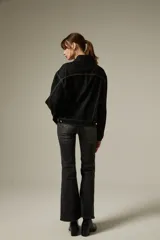 Campera de jean color negro con costuras a contratono, diseño de corte holgado, cuello camisero, cierre frontal con botones metálicos y dos bolsillos frontales con solapa.