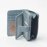 Billetera de mujer confeccionada en tela denim con diseño patchwork en tonos celestes y azules, cierre perimetral con cremallera y solapa frontal con broche magnético.