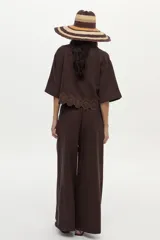 Pantalón marrón de tiro alto y pierna ancha, con detalle acordonado en la cintura y pinzas.