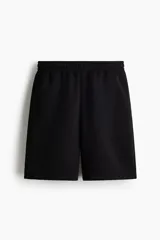 Short de felpa interlock negro, de corte relajado a la rodilla, con cintura elástica con cordón ajustable oculto, bolsillos laterales y bolsillo trasero.