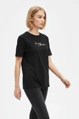 Remera negra de algodón con cuello redondo, manga corta y estampa frontal con texto en blanco.