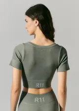 Top deportivo corto color verde militar, de morley sin costuras, con escote en V y mangas cortas.