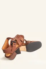 Sandalia de cuero vacuno texturado color negro, con tiras anchas y hebilla lateral. Taco ancho de madera.