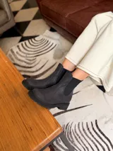 Bota tipo chelsea de cuero negro, con paneles elásticos laterales y suela track dentada.