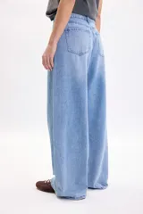 Pantalón wide leg de denim azul medio, de tiro medio con pinzas en la parte delantera y corte ancho en las piernas.