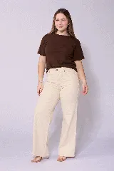 Jean de corte wide leg en color beige, con tiro alto y cierre frontal con botón y cremallera. Presenta un diseño de cinco bolsillos y costuras reforzadas.