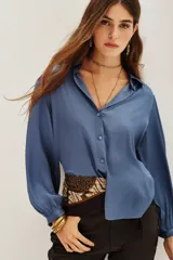 Camisa de viscosa con acabado satinado, color azul, de corte clásico con cuello camisero, cierre frontal de botones y mangas largas con puños ajustados.