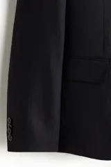 Blazer slim fit de lino liviano color negro, con solapas de muesca, botonadura sencilla de dos botones y bolsillos con solapa.