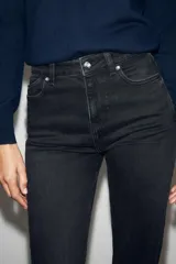 Jeans mom fit de tiro alto color negro con efecto lavado, diseño de cinco bolsillos y corte tobillero.