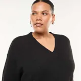 Sweater de punto negro con cuello en V y puños acanalados, de corte holgado y manga larga.