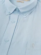 Camisa celeste de lino, de manga larga, con cuello abotonado y bolsillo en el pecho.