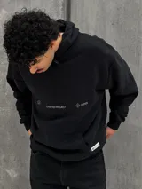 Canguro negro con capucha ajustable con cordones, bolsillo tipo canguro y estampado frontal con el texto "Crafted Project" y símbolos gráficos.