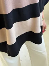 Poncho de tejido de punto con diseño de rayas horizontales anchas en color negro y beige, de corte holgado y mangas anchas.