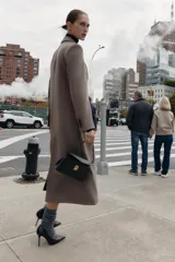 Bolso de mano mini estructurado en color negro, con asa superior fija y cierre frontal mediante clip metálico dorado. Incluye bandolera extraíble y bolsillo interior.