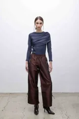 Pantalón marrón de tafeta tornasolada, corte recto y cintura elastizada. Cuenta con bolsillos frontales con cierre y cordones ajustables en las pantorrillas.