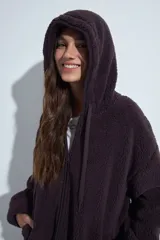 Canguro de corderito con capucha, cierre frontal y bolsillos laterales. Diseño relajado y textura suave.