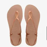 Ojotas Havaianas modelo Luna, color cobre metalizado, con tiras finas que se cruzan alrededor del tobillo y un detalle ovalado en la parte frontal que se repite en la suela.