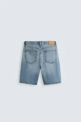 Bermuda de denim de algodón, color verde claro lavado, de corte recto y tiro medio. Presenta cinco bolsillos y cierre frontal con cremallera y botón.