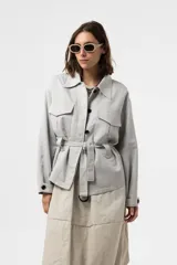 Chaqueta de calce relajado y estilo utilitario, color gris, con bolsillos delanteros grandes con solapa y cinturón ajustable en la cintura.