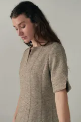 Vestido a la rodilla color beige, con escote en V, mangas 3/4 y bolsillos laterales.