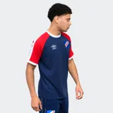 Remera de algodón azul con mangas raglán rojas y detalles en blanco en cuello y puños. Incluye logo de Umbro bordado en el pecho y escudo del Club Nacional de Football.