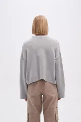 Cardigan de tejido de punto gris, con cuello redondo, cierre frontal con botones y mangas largas de corte holgado.