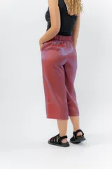 Pantalón de lino con acabado metalizado tornasolado, que refleja tonos entre rosa y lila según la luz. De corte recto y largo ¾, tiene cintura con elástico en la espalda que aporta comodidad y un calce relajado.