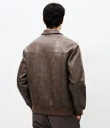 Campera de poliuretano con acabado lavado, diseño de corte regular, cuello camisero, cierre frontal, puños y cintura con rib elástico.